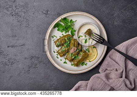 Top View Dolma With Parsley And Lemon In Light Plate With With Sour Cream, On Black Fork Pricked Pie
