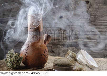 Old Brown Steamung Bong And Open Cannabis Grinder With Chopped Marijuana Weed And Medical Cannabis B