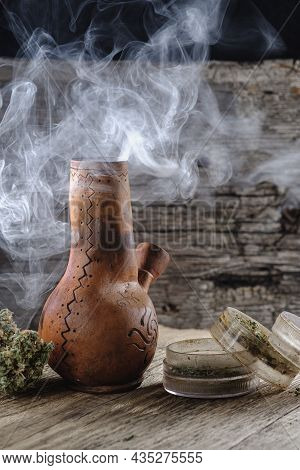 Old Brown Steamung Bong And Open Cannabis Grinder With Chopped Marijuana Weed And Medical Cannabis B
