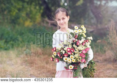 A Girl Holds In Her Hands A Large Beautiful Bouquet Of Autumn Flowers In A White Sweater In A Forest