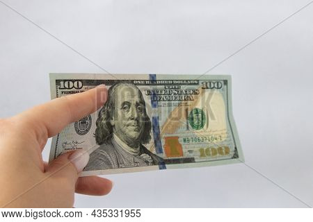 100 Dollars In Hand Close-up On A White Isolated Background. A Hundred-dollar Bill