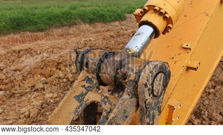 Old Pivot Joints And Axel Piston. Yellow Excavator Metal Bolts And Hydraulic Axle Shafts On The Grou