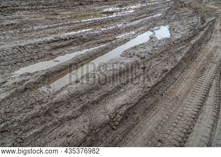 A Broken Rural Country Road. Puddles After Rain On A Dirt Road. Clay, Soil And Puddles At Cloudy Day