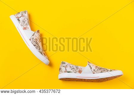 Pair Of Female's New Stylish Slip-ons With Floral Ornament On A Yellow Background. Flat Lay. Copy Sp