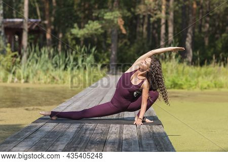 A Woman In Sportswear Practicing Yoga Performs The Skandasana Or Surfer Lunge Exercise In The Park O