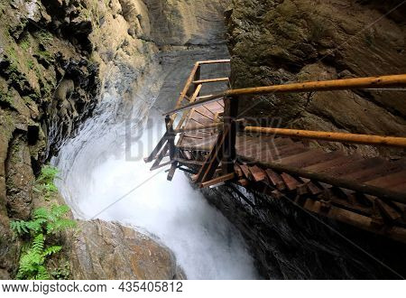 Wooden Walkpath As Bridge Over Cascading Waterfall
