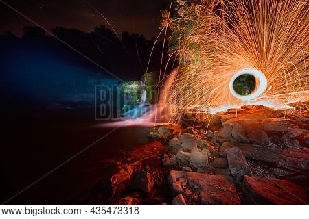 Eerily Glowing Waterfall At Night With Yellow Orb Of Sparks