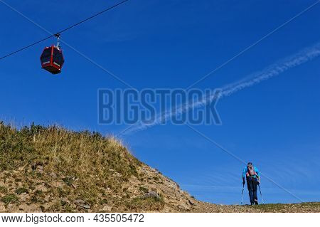 Chamrousse, France, September 13, 2021 : The Hiker On A Hard Slope And The Cable-car Cabin