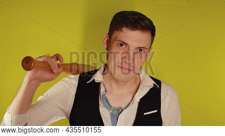 Man On Strict Face Posing With Wooden Bat. A Man In A Business Strict Elegant Suit With A Wooden Bat