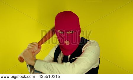 Man In Pink Balaclava With Baseball Bat. Hooligan In Mask With Bat In Hands. A Man In A Business Str