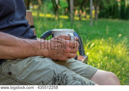 Male Strong Wiry Hand Holding Cup Against Green Nature Background, Hand Of 60 Year Old Man