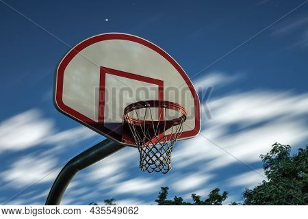 A Long Exposure Photograph Of A Dirty Orange And White Playground Basketball Hoop, Rim And Net With