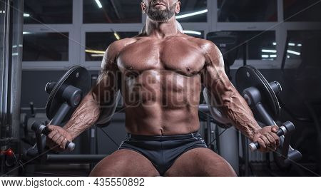 Noname Image Of A Powerful Athlete Sitting On A Bench In A Gym And Pumping Biceps. Fitness And Bodyb