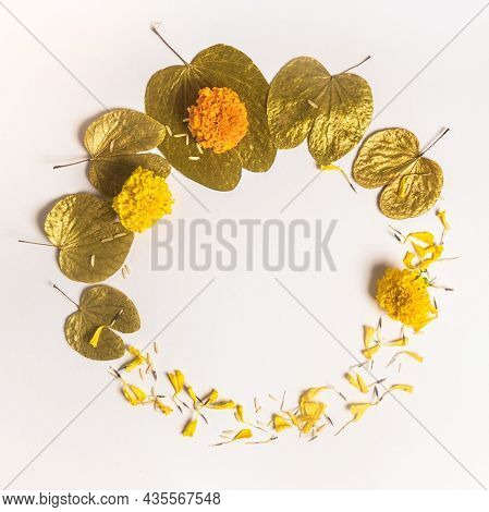 Dussehra greetings background unit with clear space for message.  Golden Apta leaves and marigold flowers arranged in a circular shape with empty space for logo or text.