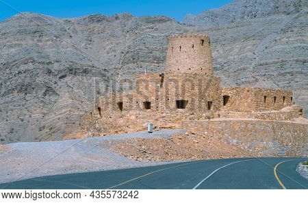 Stone Walls Of Small Medieval Arabian Fort Under Tall Mountain Cliffs. Fortress In Bukha, Musandam P