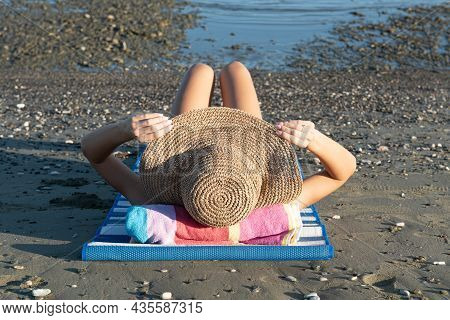Young Unrecognized Caucasian Woman Wearing A Hat Reasting On The Beach. Summer Vacations, Relaxing O