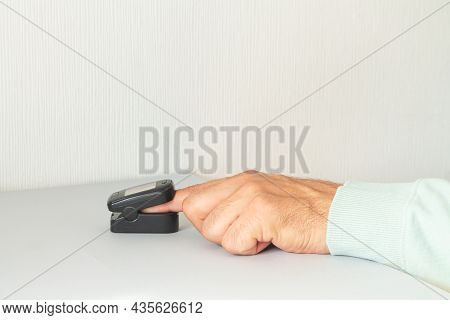 Man Checking Blood Oxygen Level With Pulse Oximeter At Home. Health Control Concept