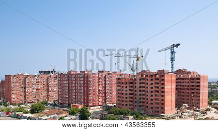 The elevating crane against the dark blue sky building a monolithic building.