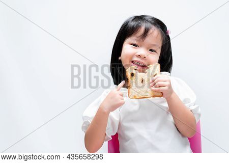 A Sweet Smiling Little Girl, A Child Holding A Raisin Bread, Kid Pointing A Finger At The Bread, Chi