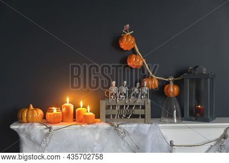 Halloween Home Decoration. Plastic Toy Skeletons In A Wooden Box On A Fireplace Against A Dark Blue
