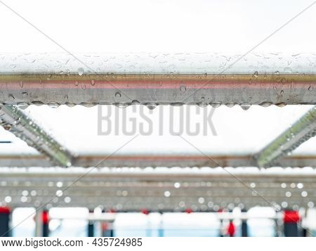 Stainless Steel Pipe Of Handrail In Detail. Morning Rain Drops Hanging And Shining Against Gray Sky