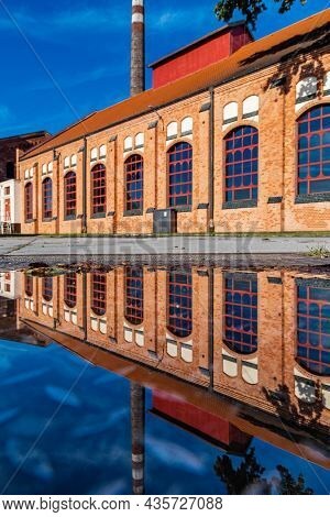 Wroclaw, Poland - September 2 2020: Facade Of Old Pumping Station Building Reflected In Puddle