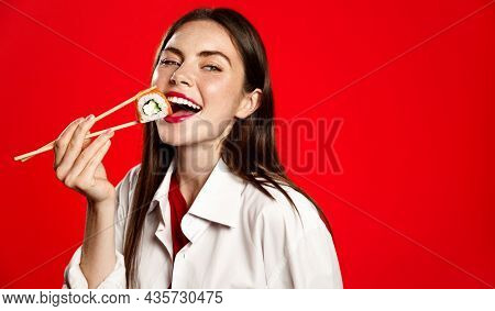 Beautiful Girl Eating Japanese Sushi Rolls With Chopsticks, Smiling From Satisfaction, Order In Oria