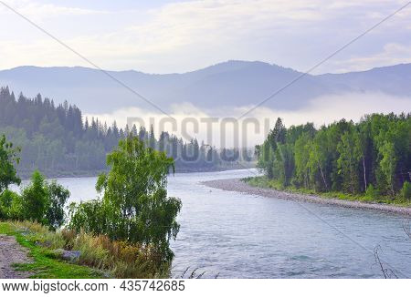 The Bank Of A Mountain River Under A Blue Cloudy Sky. Altai, Siberia, Russia