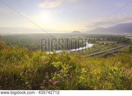 A Blooming Mountain Slope In The Uimon Valley. Bright Wildflowers In The Morning Light Under The Blu