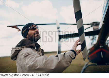 Portrait Of Helicopter Pilot Standing Near Vehicle In Field Airport.