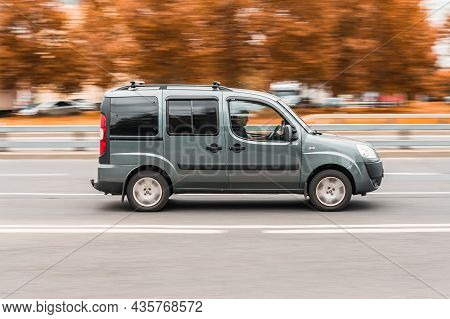Fiat Doblo Rides On The City Road With Autumn Trees Background. Family Mpv Fiat Doblo In Motion. Mos