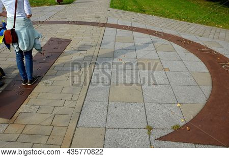 Sundial On The Square. The Hand Of The Drop Shadow Is Formed By A Man Standing In The Center Of The 