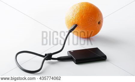 The External Ssd Is Wired To A Fresh Orange. The Concept Of Green Technologies, Greentech And Data T