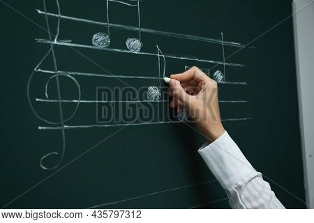 Teacher Writing Music Notes With Chalk On Greenboard, Closeup