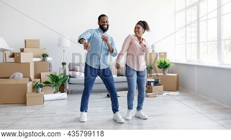 Satisfied Young African American Husband And Wife Dancing In New Apartment With Cardboard Boxes
