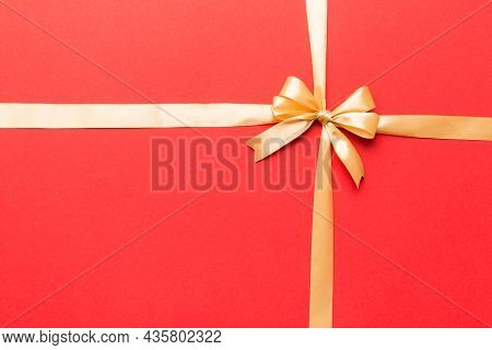 Top View Of Gold Ribbon Rolled And Yellowbow Isolated On Colored Background. Flat Lay With Copy Spac