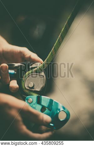 Man's Hands Operating A Rock Climbing Belaying Device