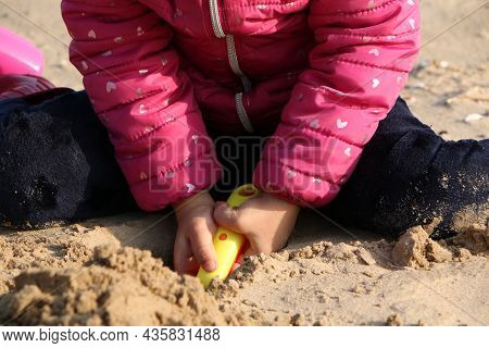 Child Girl Playing By The Sea In Autumn. A Girl In A Red Jacket In A Beautiful Autumn On The Seashor