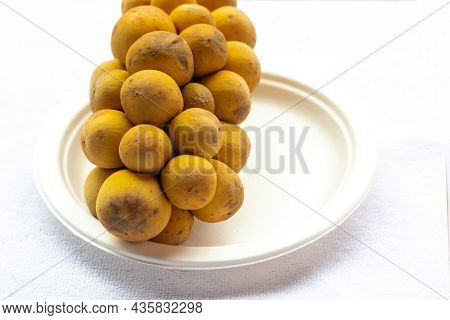 Longong Yellow Fruit Branch Lies On A White Plate On A White Background