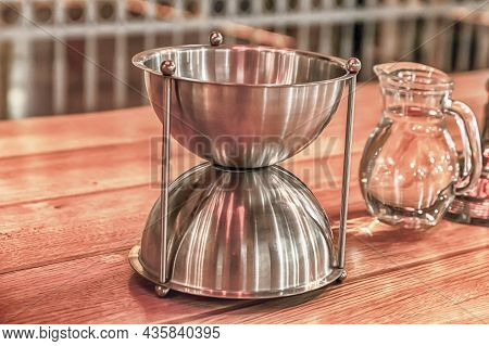 An Hourglass-shaped Iron Bowl Stands Next To A Carafe Of Water; A Traditional Wine Tasting Set