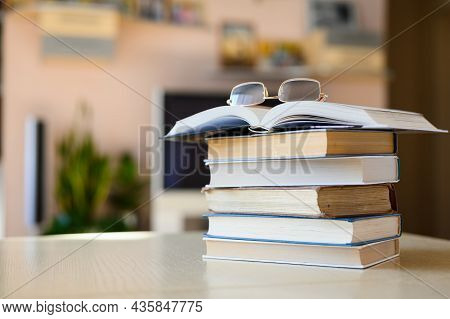 Stack Of Books And Glasses On The Table In The Room. Open Book With Glasses. Selective Focus On The 