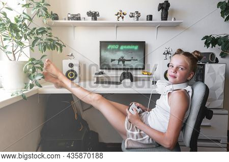 Girl Holding White Wireless Gamepad Against White Computer Dream Desk.