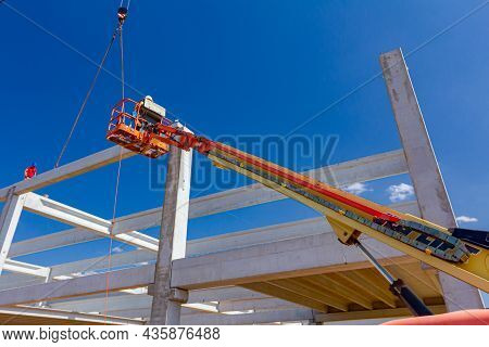 Mobile Crane Is Operating And Worker Is Assembly Concrete Joist In High Place. Height Worker Is Plac