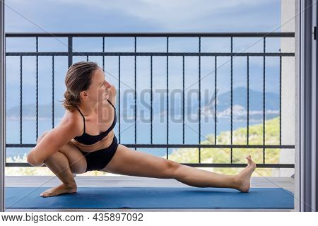 Young Fitness Woman Doing Morning Yoga Practice At The Balcony Near The Sea