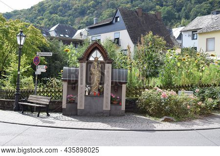 Treis-karden, Germany - 09 21 2021: Village Road With Resting Area And Religious Statue