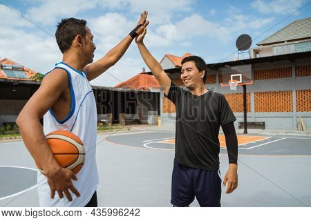 Two Male Basketball Players With High Fives At Break Playing Basketball