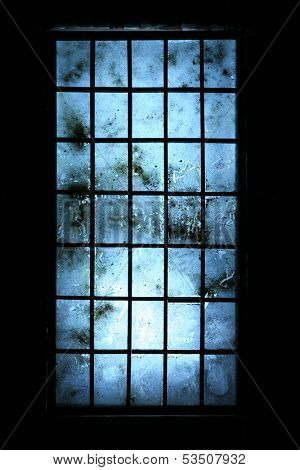 Big old dirty window with blue scratched glasses in dark room.