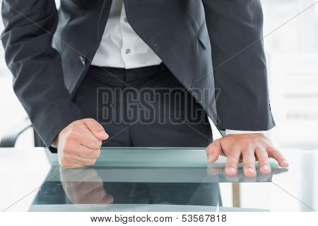 Close up mid section of a well dressed businessman with clenched fist on the desk at office