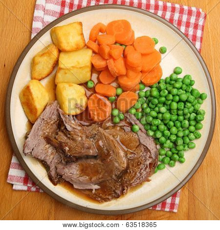 Roast lamb dinner with vegetables and gravy.