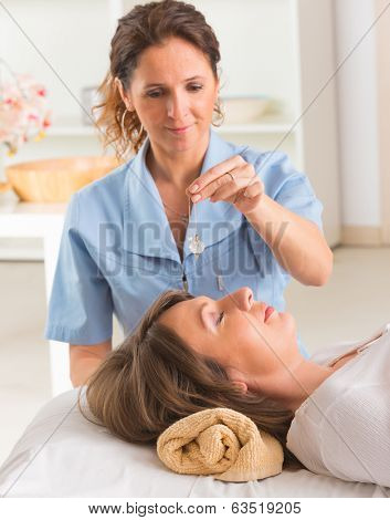 Alternative medicine therapist using pendulum to make a diagnosis